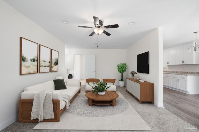 living area featuring baseboards and ceiling fan