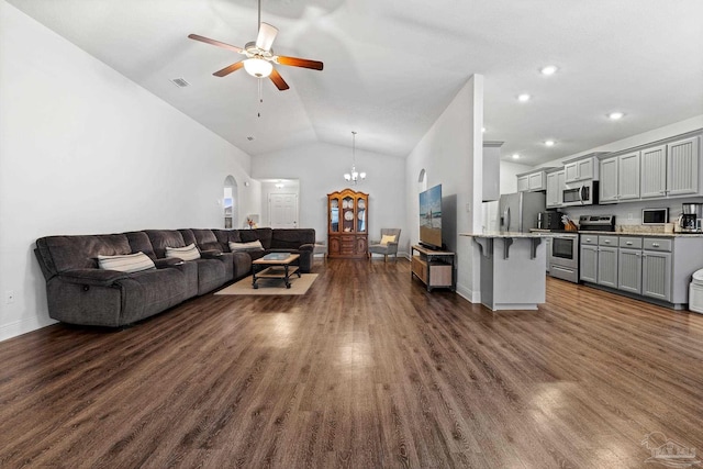 living room with ceiling fan with notable chandelier, dark wood-type flooring, and vaulted ceiling