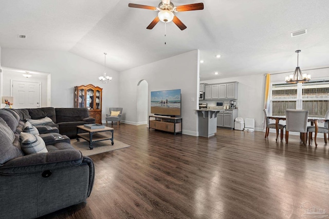 living room with ceiling fan with notable chandelier, dark hardwood / wood-style flooring, and vaulted ceiling