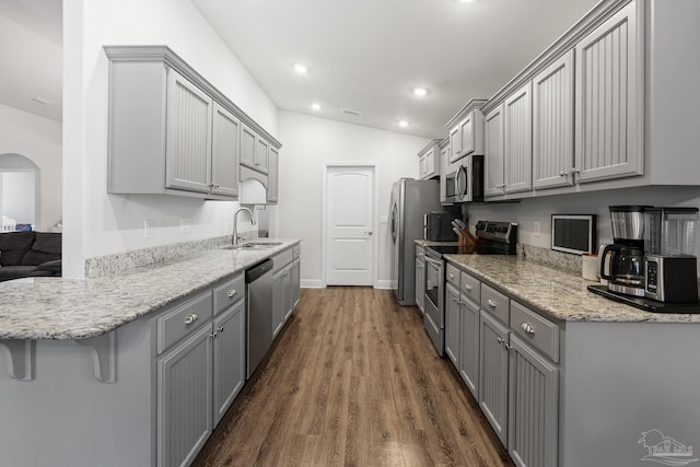 kitchen featuring gray cabinetry, lofted ceiling, sink, a kitchen bar, and stainless steel appliances