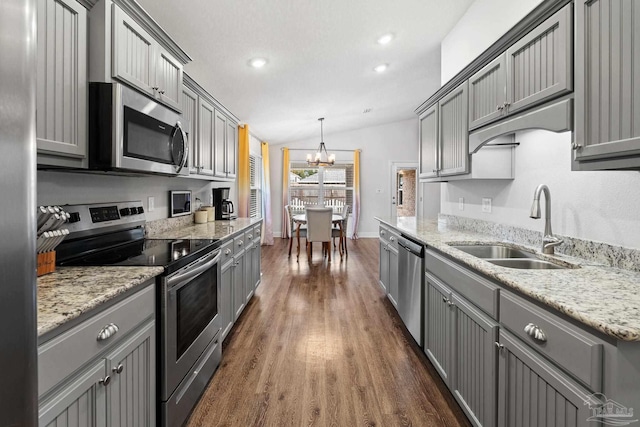 kitchen with lofted ceiling, sink, hanging light fixtures, gray cabinets, and appliances with stainless steel finishes