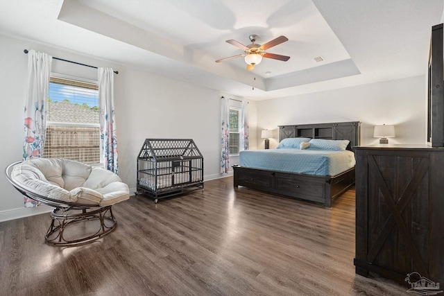 bedroom featuring a tray ceiling, ceiling fan, and dark wood-type flooring