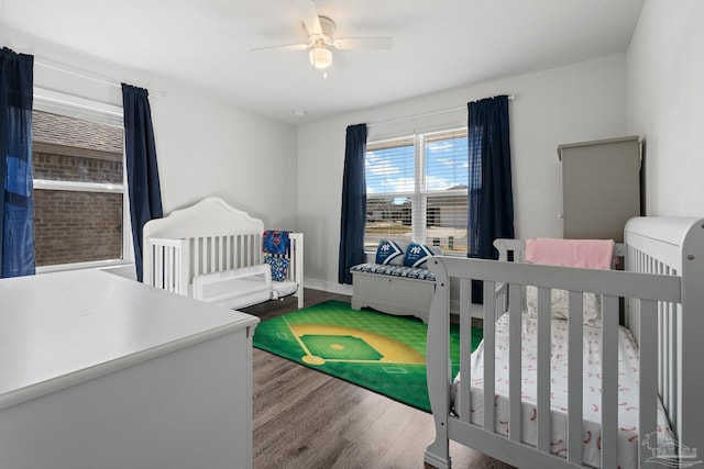 bedroom with wood-type flooring, a nursery area, and ceiling fan