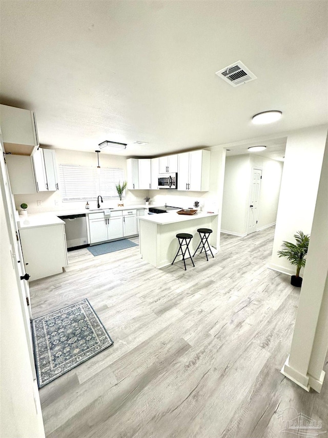 kitchen with white cabinetry, dishwasher, a center island, sink, and a breakfast bar area