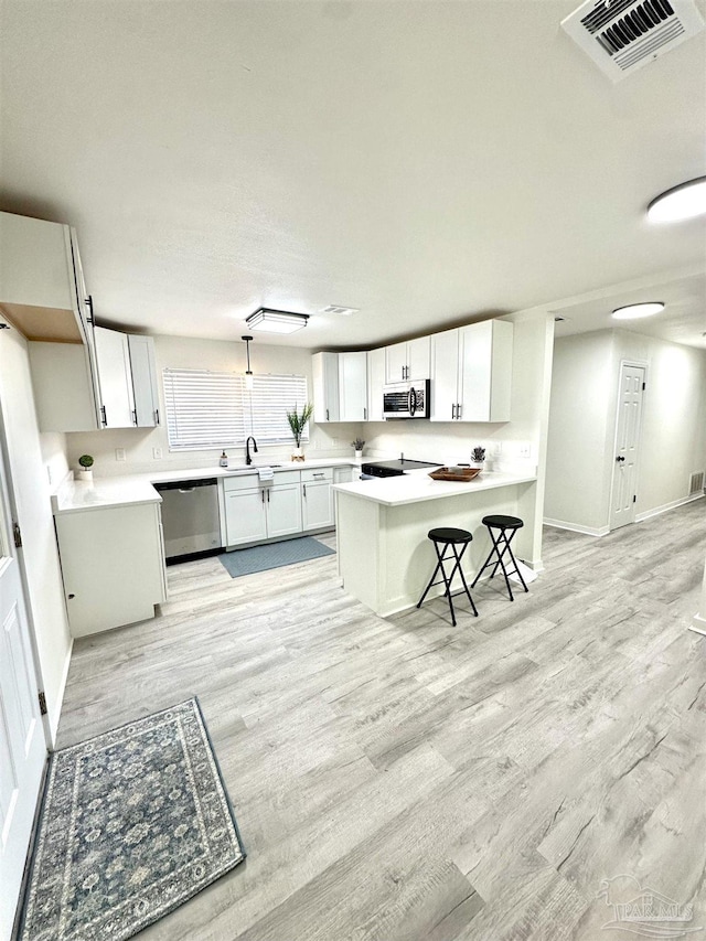 kitchen featuring appliances with stainless steel finishes, a kitchen breakfast bar, sink, white cabinets, and a center island