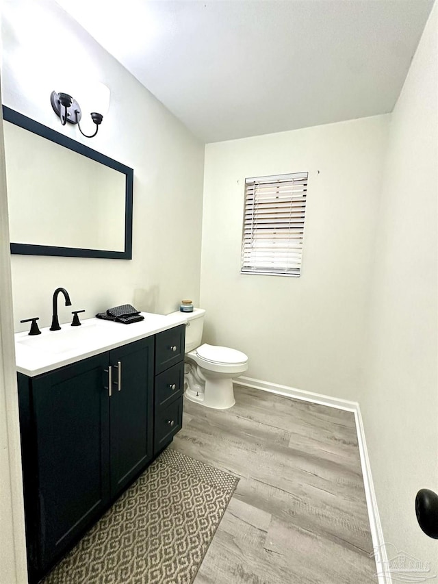 bathroom featuring toilet, vanity, and hardwood / wood-style flooring