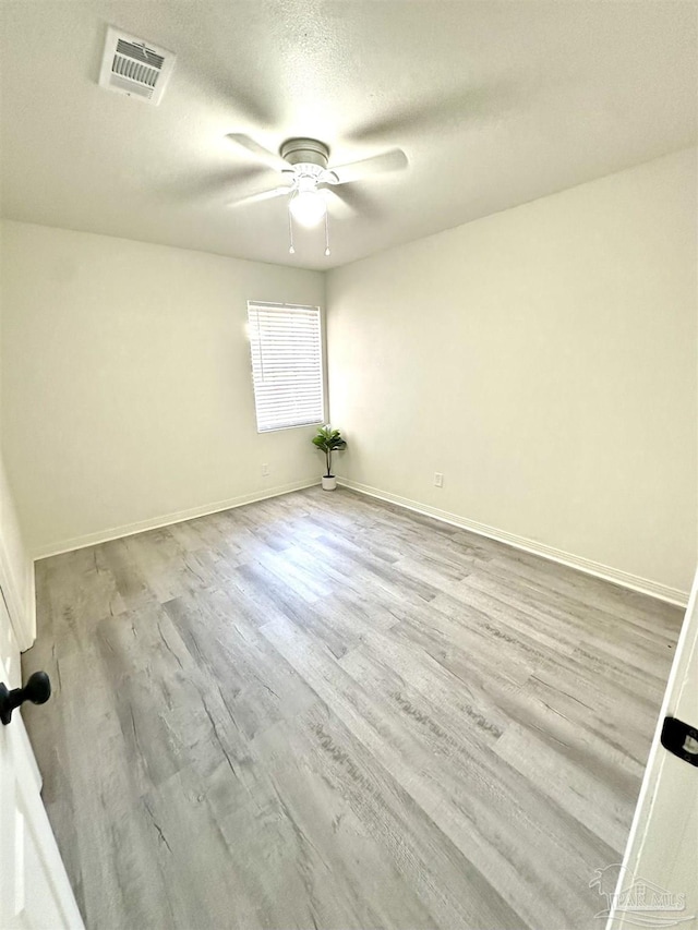 spare room featuring light wood-type flooring, a textured ceiling, and ceiling fan