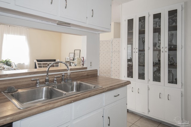 kitchen with white cabinetry, sink, wooden counters, and light tile patterned flooring