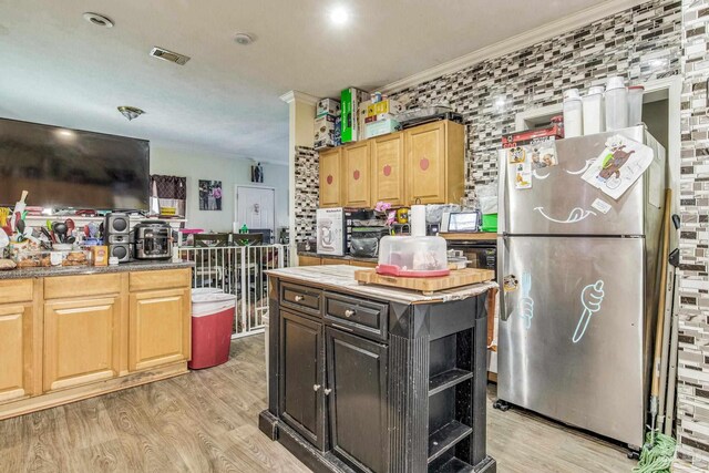 kitchen with light hardwood / wood-style flooring, ornamental molding, a center island, and stainless steel refrigerator