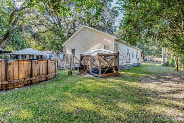 rear view of house with a wooden deck, a lawn, and central AC unit