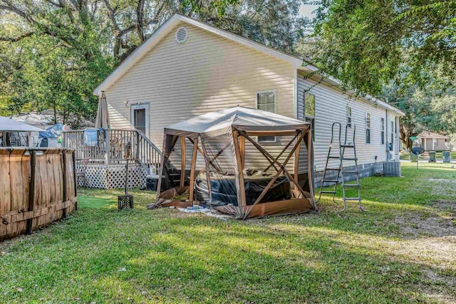 back of house with a wooden deck, central AC unit, and a lawn