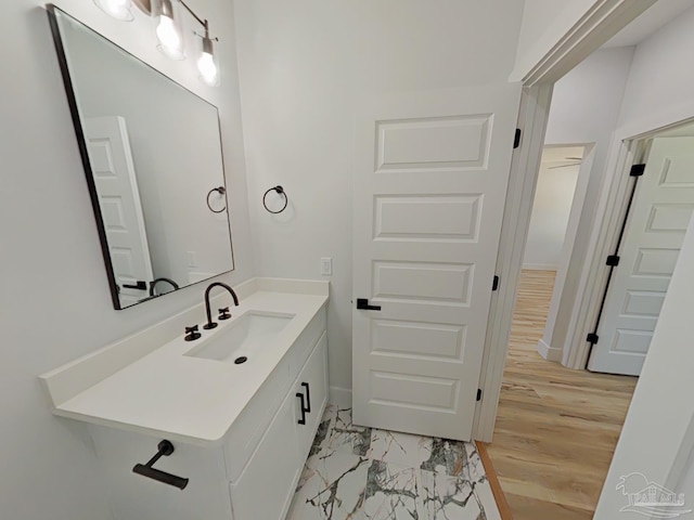 bathroom with marble finish floor, vanity, and baseboards