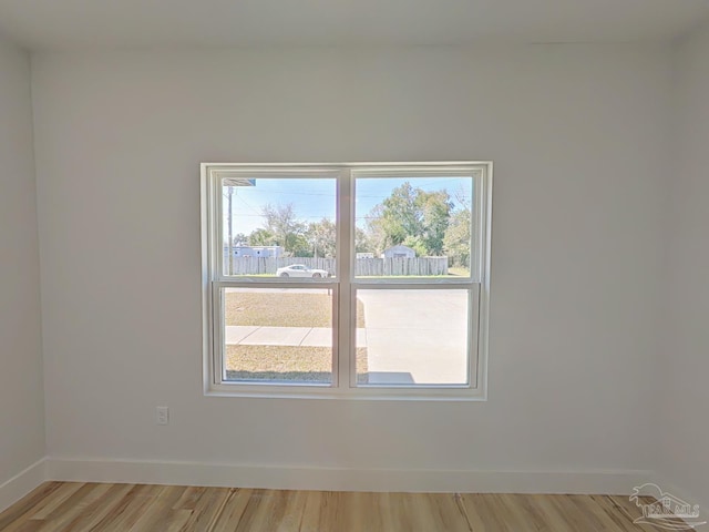 empty room with light wood-style floors, a healthy amount of sunlight, and baseboards