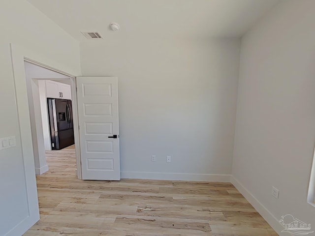 empty room featuring light wood finished floors, baseboards, and visible vents