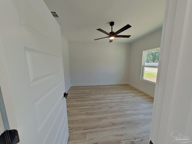 unfurnished room with visible vents, a ceiling fan, light wood-style flooring, and baseboards