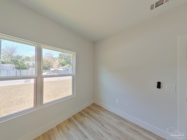 unfurnished room with light wood-style flooring, visible vents, and baseboards