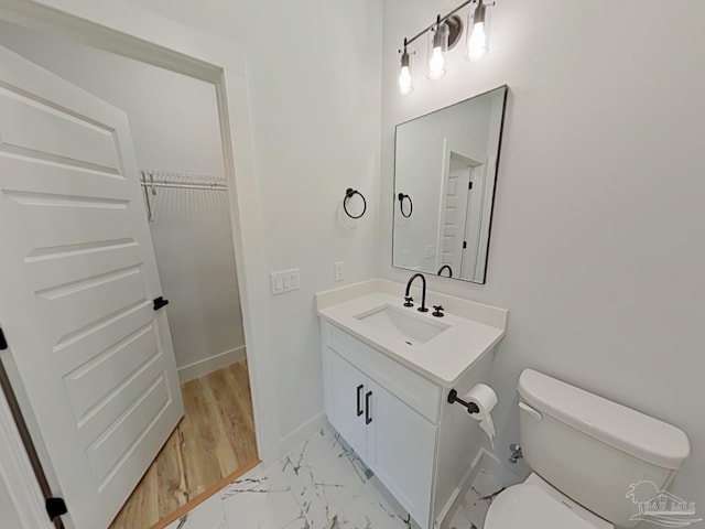 bathroom featuring toilet, marble finish floor, baseboards, and vanity