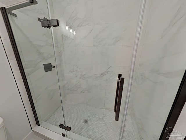 bathroom with toilet and a marble finish shower