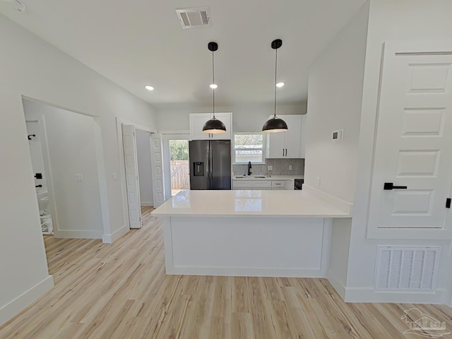 kitchen featuring a peninsula, light countertops, stainless steel fridge, and visible vents