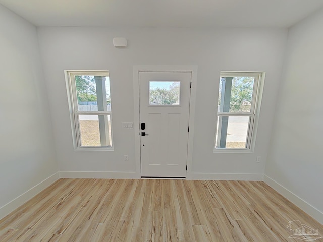 foyer entrance with light wood-style flooring, baseboards, and a wealth of natural light