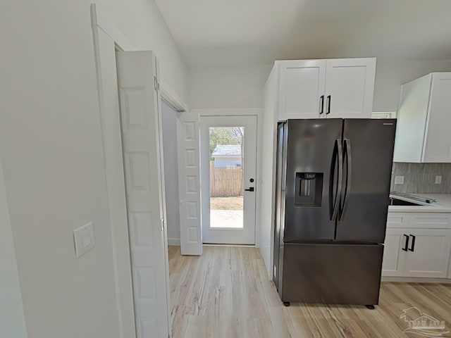 kitchen with backsplash, white cabinetry, fridge with ice dispenser, and light wood-style flooring