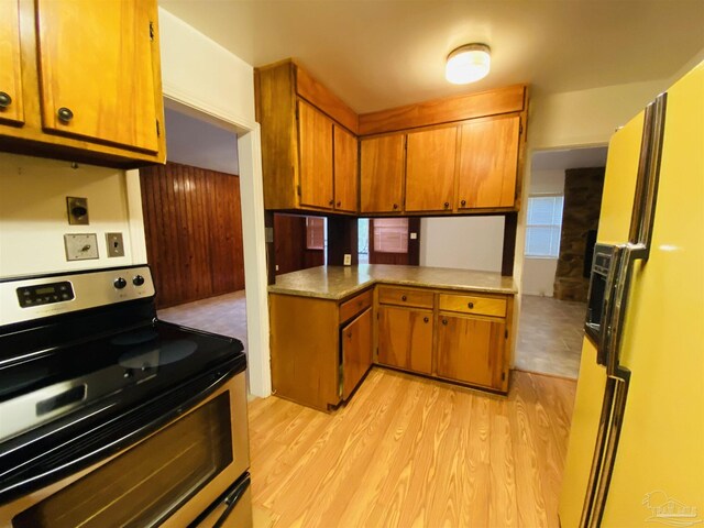 kitchen featuring wooden walls, kitchen peninsula, and white fridge with ice dispenser