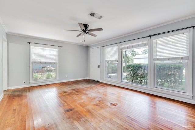 unfurnished room featuring light wood finished floors, visible vents, a healthy amount of sunlight, and crown molding