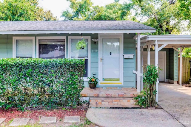 entrance to property with driveway and a shingled roof