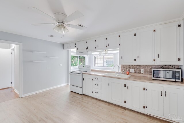 kitchen featuring island range hood, sink, light wood-type flooring, white electric range oven, and ceiling fan