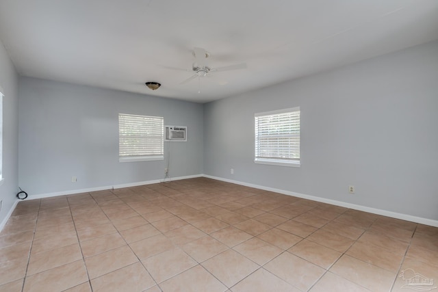 empty room featuring a wealth of natural light, baseboards, ceiling fan, and a wall unit AC