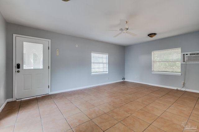 interior space featuring baseboards, a wall mounted AC, and a ceiling fan