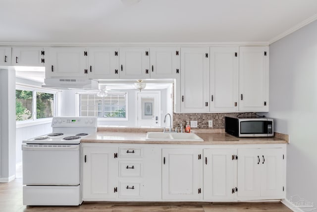 kitchen with electric range, white cabinetry, exhaust hood, and a sink