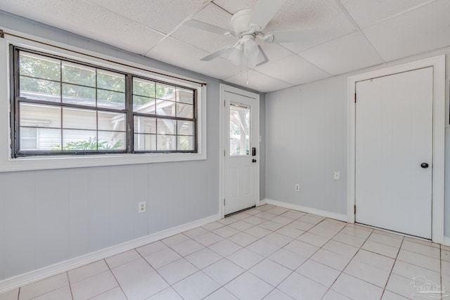 spare room with a drop ceiling, baseboards, ceiling fan, and light tile patterned flooring