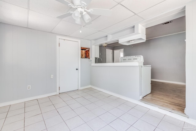 empty room with visible vents, baseboards, washer / clothes dryer, a paneled ceiling, and a ceiling fan