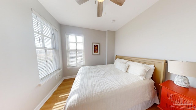 bedroom featuring light wood-type flooring, baseboards, a ceiling fan, and lofted ceiling