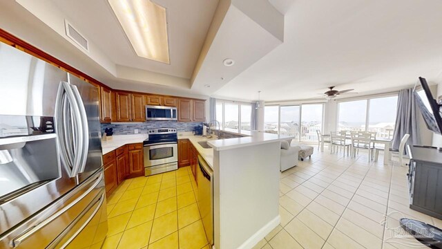 kitchen with light tile patterned floors, stainless steel appliances, a peninsula, visible vents, and backsplash