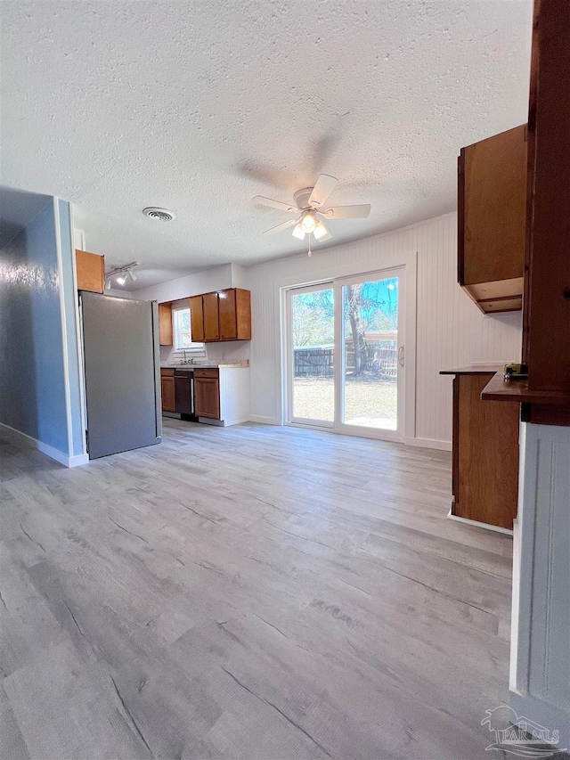 kitchen featuring brown cabinetry, open floor plan, light wood-style floors, and freestanding refrigerator