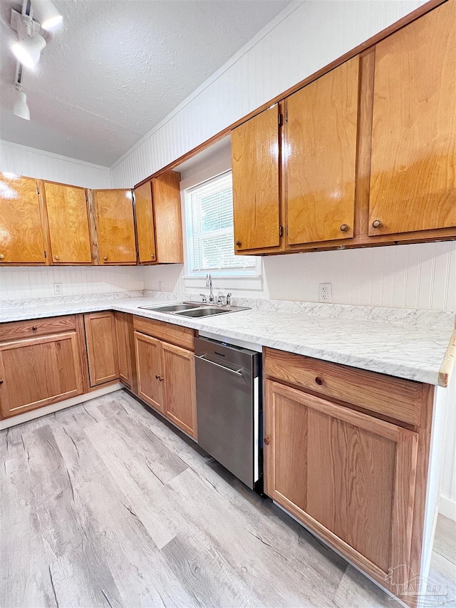 kitchen featuring light wood finished floors, brown cabinets, a textured ceiling, stainless steel dishwasher, and a sink