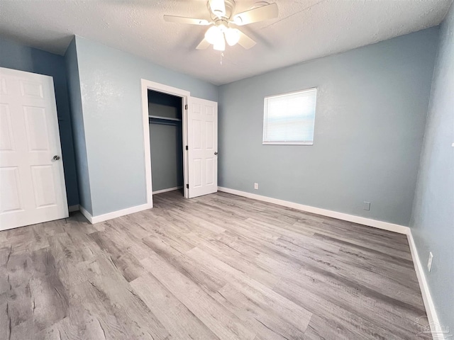 unfurnished bedroom featuring a closet, a textured ceiling, baseboards, and wood finished floors