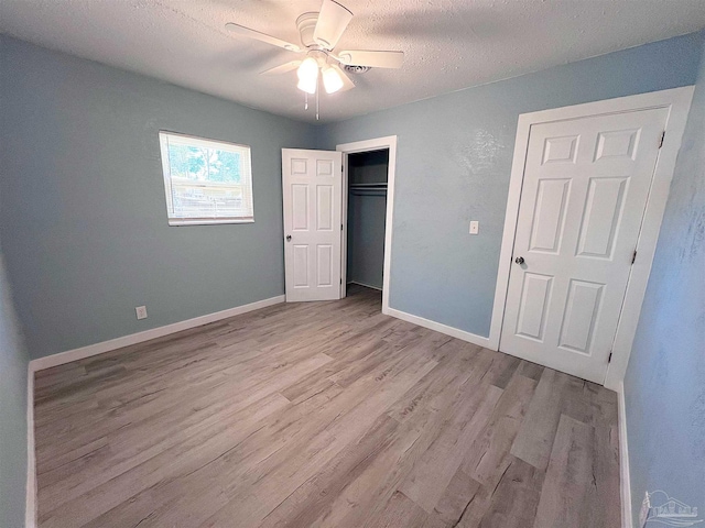 unfurnished bedroom featuring light wood finished floors, baseboards, a ceiling fan, a textured ceiling, and a closet