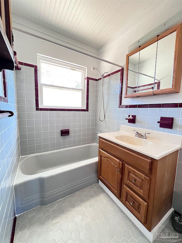 full bath featuring washtub / shower combination, tile walls, vanity, and tile patterned floors