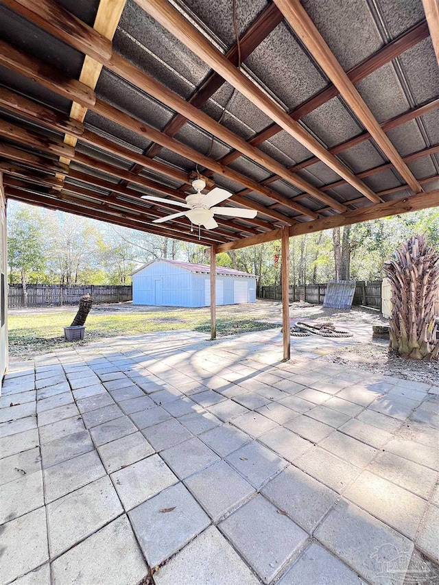 view of patio / terrace featuring a shed, a ceiling fan, a fenced backyard, and an outdoor structure