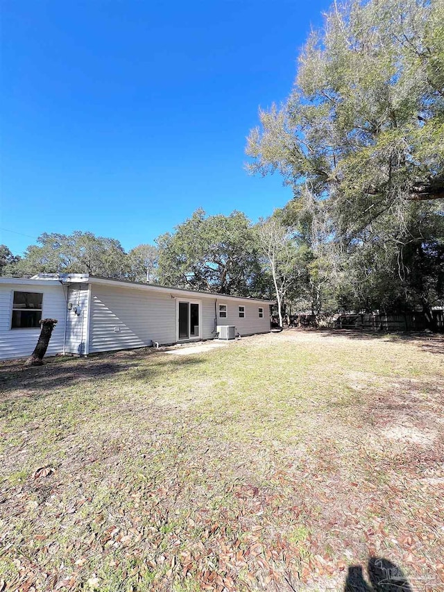 back of house with central air condition unit and a yard