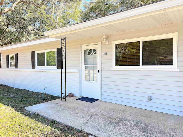 view of exterior entry with a patio area and brick siding