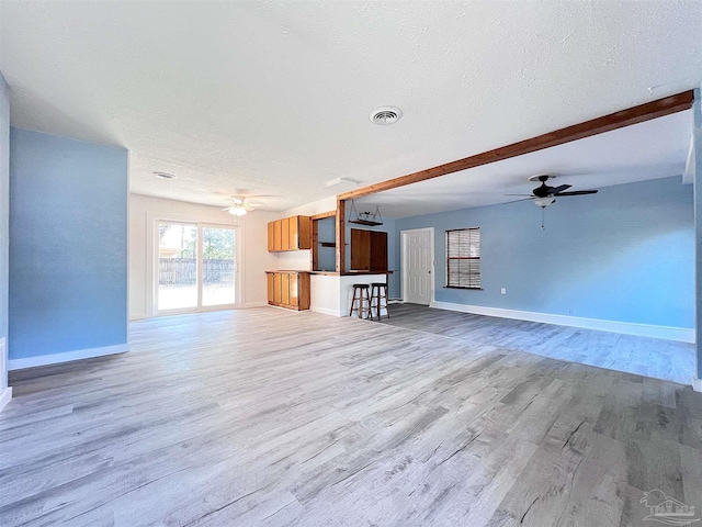 unfurnished living room featuring visible vents, light wood-style flooring, and a textured ceiling