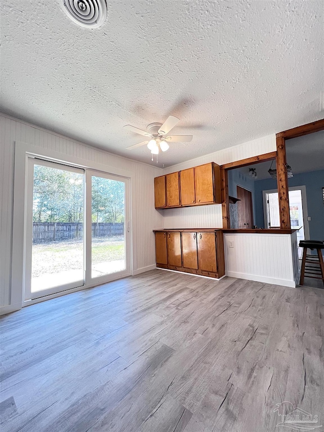 unfurnished living room featuring a ceiling fan, visible vents, light wood-style flooring, and a textured ceiling