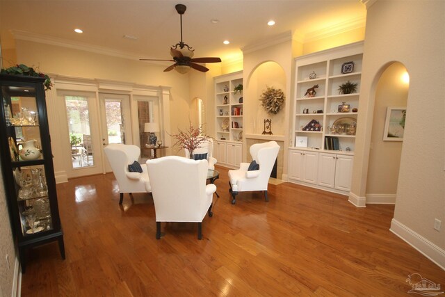 living area featuring arched walkways, ceiling fan, and ornamental molding