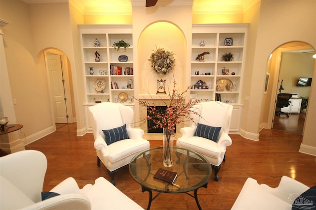 sitting room with arched walkways, wood finished floors, and baseboards