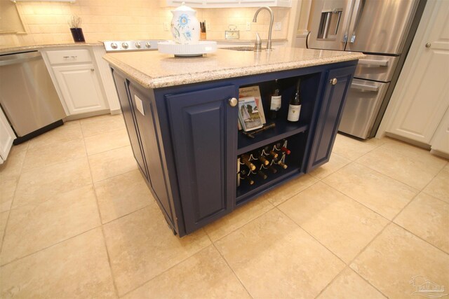 kitchen with tasteful backsplash, appliances with stainless steel finishes, white cabinetry, and a sink