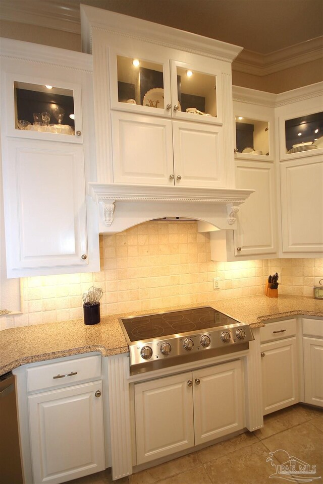 kitchen featuring stovetop, white cabinetry, decorative backsplash, and ornamental molding